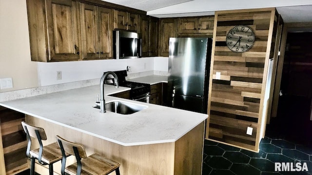 kitchen with a sink, light countertops, a peninsula, dark tile patterned flooring, and black appliances
