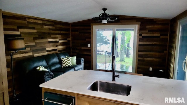 kitchen featuring a sink, wooden walls, vaulted ceiling, and light countertops