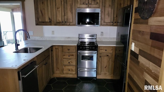 kitchen featuring a sink, light countertops, stainless steel appliances, and dark tile patterned floors