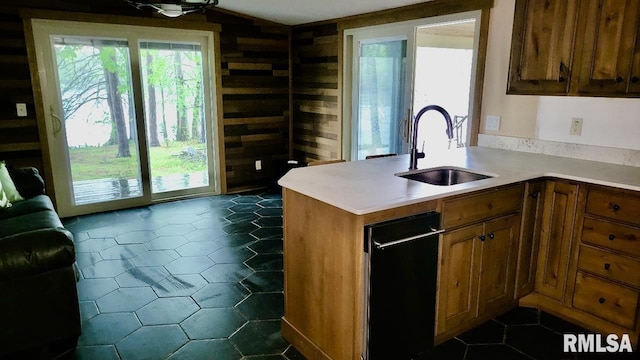 kitchen featuring a sink, brown cabinets, wood walls, and light countertops