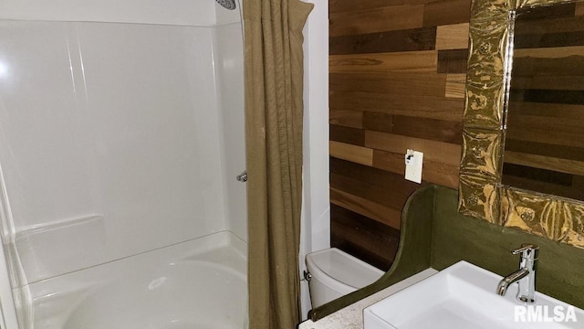 bathroom featuring wooden walls, toilet, and a sink