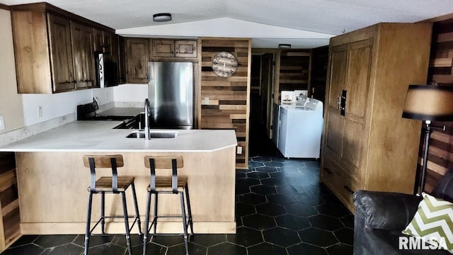 kitchen featuring electric range, a sink, light countertops, freestanding refrigerator, and a peninsula