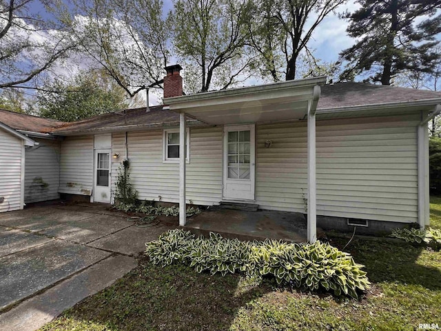 rear view of property featuring a chimney and a shingled roof