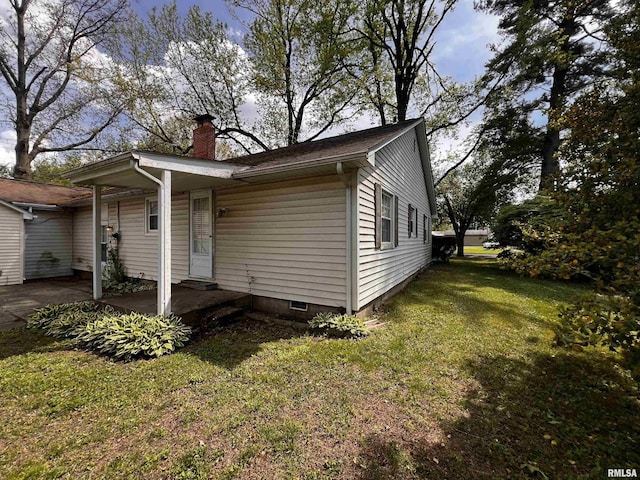 view of side of property featuring a chimney, a yard, and crawl space