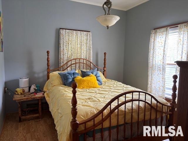 bedroom featuring ornamental molding and wood finished floors