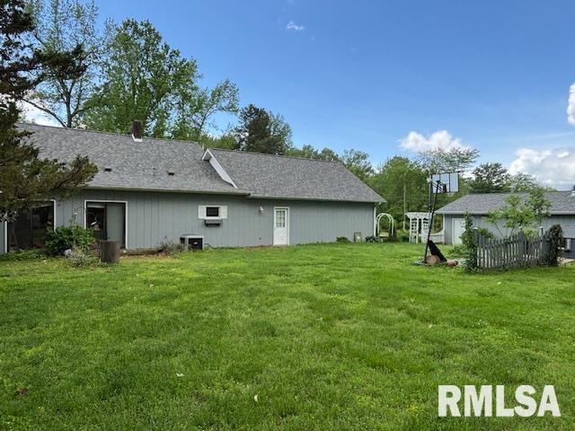rear view of property with a lawn and cooling unit