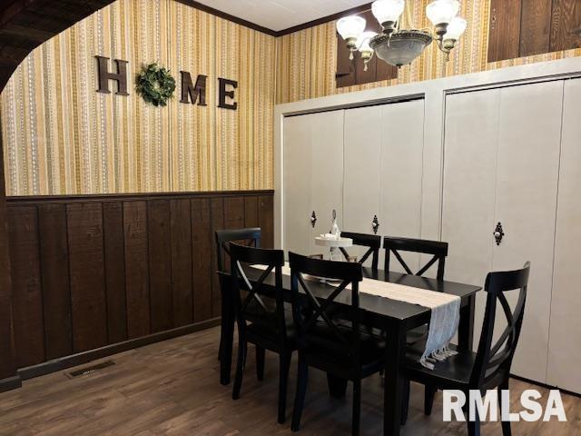 dining space featuring an inviting chandelier, a wainscoted wall, ornamental molding, and wallpapered walls