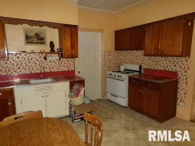 200 3rd St, Rosiclare, IL 62982 - kitchen featuring white gas range, tasteful backsplash, a sink, and light colored carpet