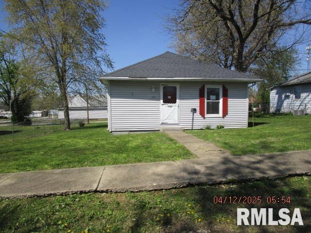 bungalow featuring a shingled roof, central AC unit, and a front lawn