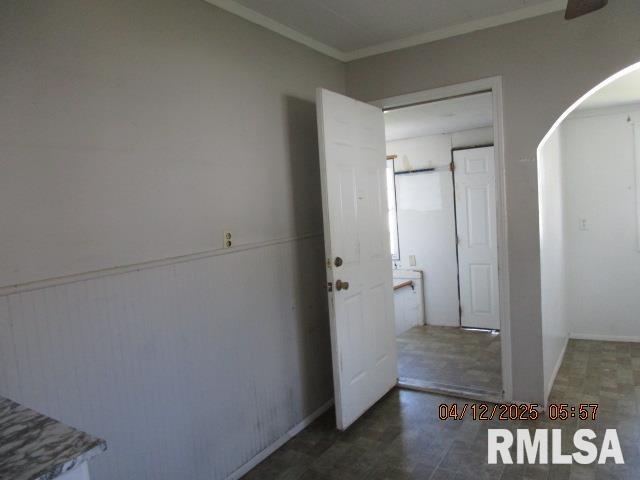 interior space featuring arched walkways, tile patterned floors, and ornamental molding