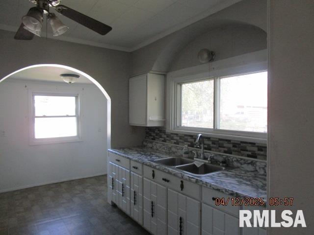 kitchen featuring ceiling fan, white cabinetry, dark floors, a sink, and backsplash