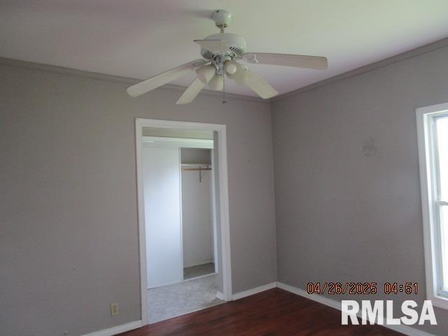 unfurnished bedroom featuring crown molding, baseboards, ceiling fan, and wood finished floors