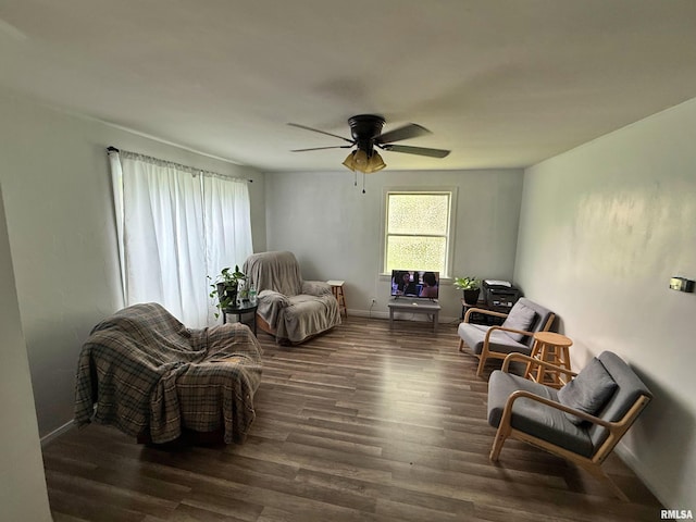 living area featuring baseboards, a ceiling fan, and wood finished floors