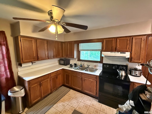 kitchen with a sink, light countertops, ventilation hood, and black appliances