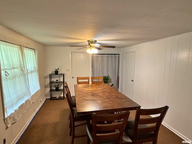 dining space featuring baseboards, a ceiling fan, and dark carpet