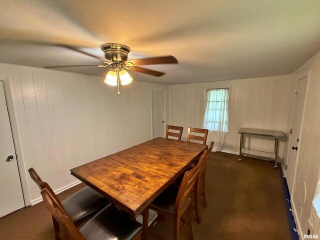 dining space with ceiling fan and dark colored carpet