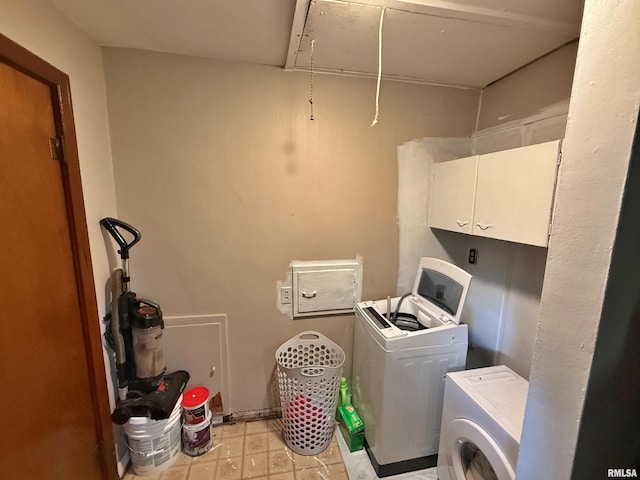 laundry room featuring light floors, attic access, cabinet space, and washer and dryer