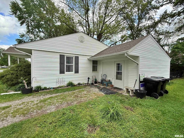 back of property featuring a lawn and roof with shingles