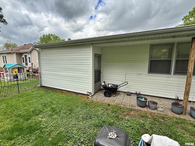 view of side of home featuring fence and a yard