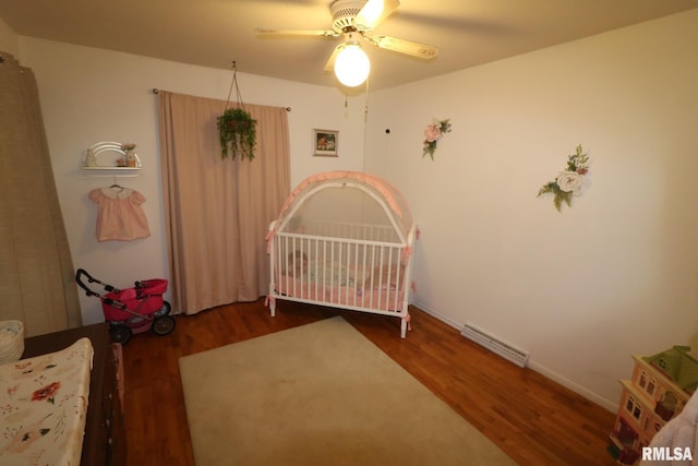 bedroom featuring a ceiling fan, visible vents, a crib, and wood finished floors