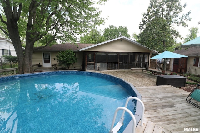 outdoor pool with a wooden deck and a sunroom