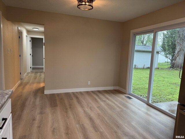 unfurnished dining area with baseboards, light wood-type flooring, and visible vents