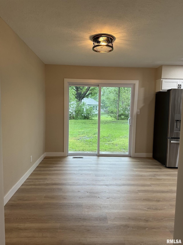 unfurnished dining area featuring baseboards, a textured ceiling, and visible vents