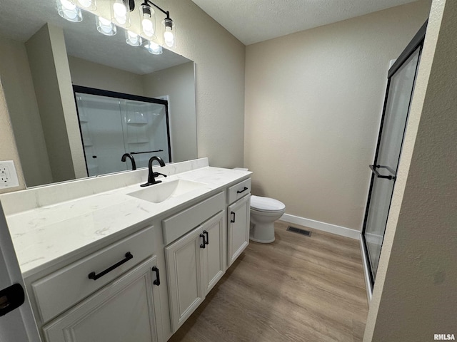 full bathroom with visible vents, vanity, wood finished floors, a textured ceiling, and a shower stall