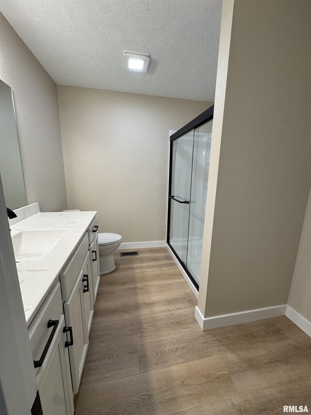 bathroom featuring vanity, a textured ceiling, wood finished floors, and a stall shower