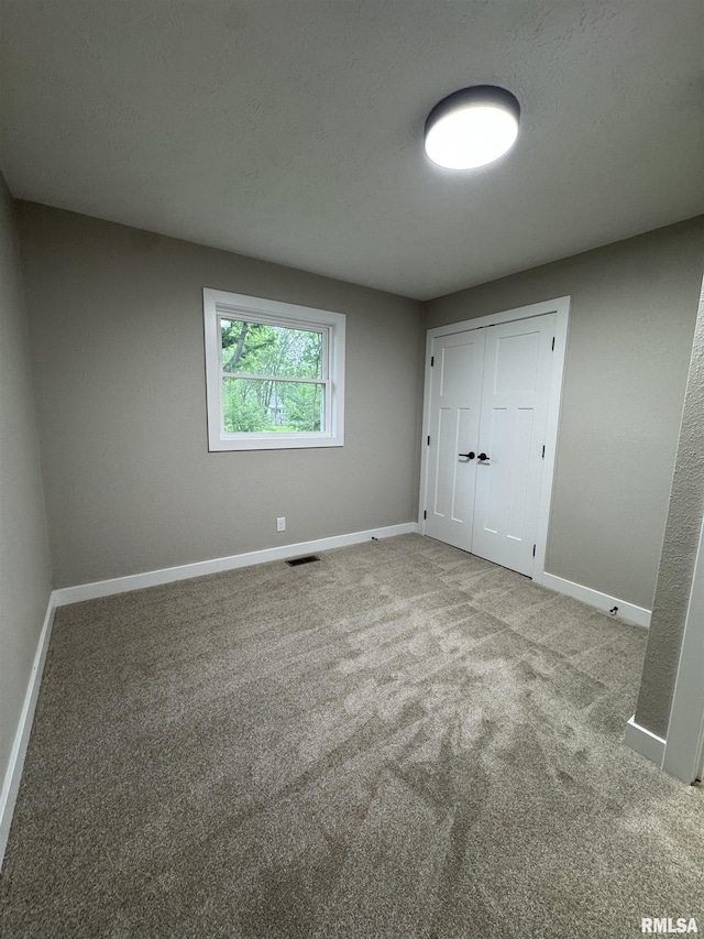 unfurnished bedroom featuring baseboards, carpet floors, and visible vents