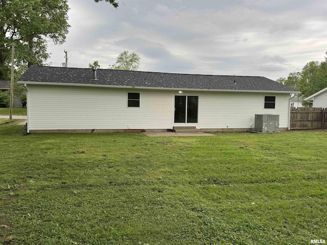 back of house featuring fence, central AC unit, and a lawn