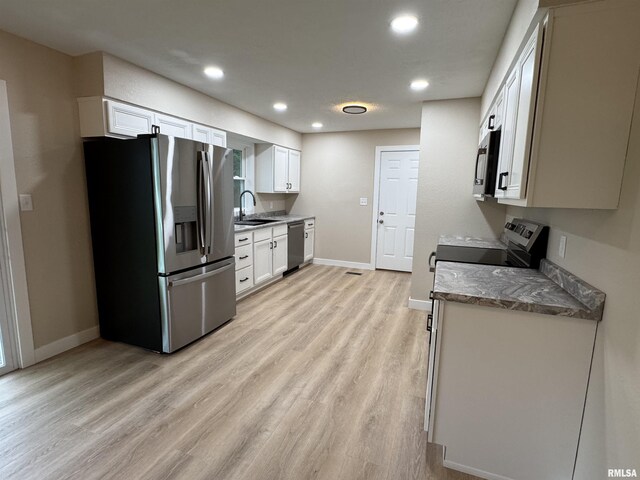 kitchen with a sink, baseboards, light wood-style floors, stainless steel appliances, and recessed lighting