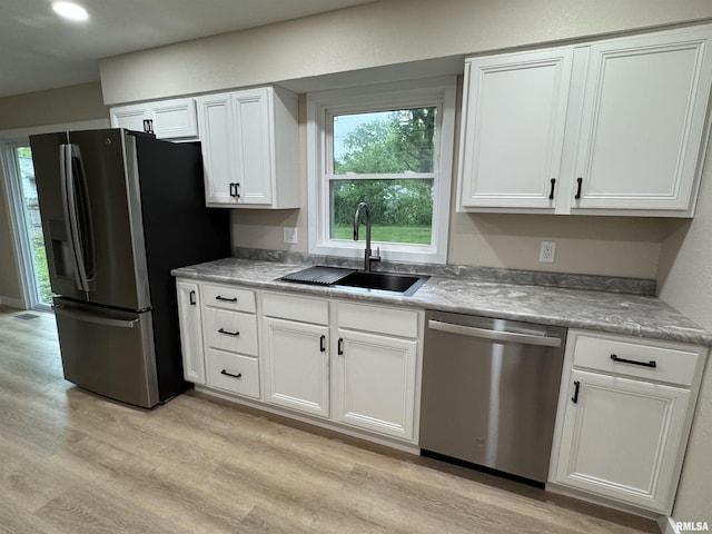 kitchen featuring light countertops, white cabinetry, a sink, light wood finished floors, and appliances with stainless steel finishes