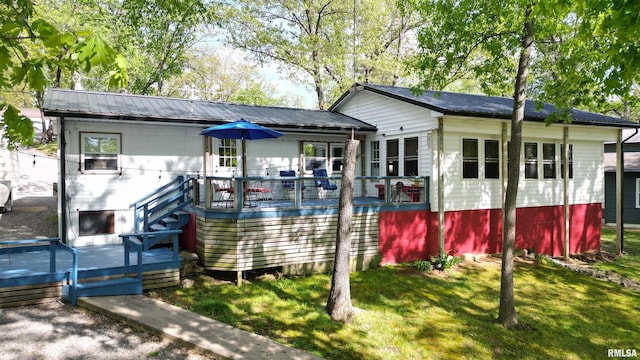 view of front facade with a deck, metal roof, and a front yard