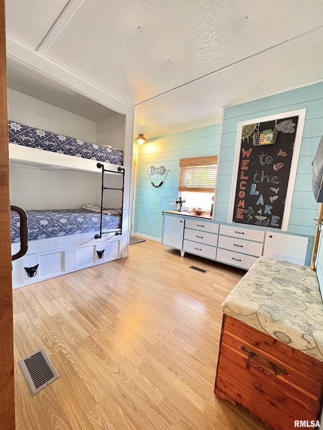 bedroom with visible vents, a textured ceiling, and wood finished floors