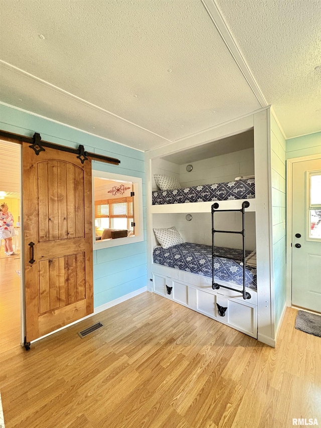 mudroom featuring a textured ceiling, visible vents, wood walls, and wood finished floors