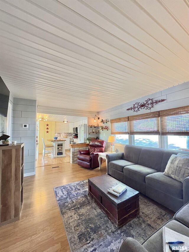 living room featuring light wood-style floors, plenty of natural light, and wood walls