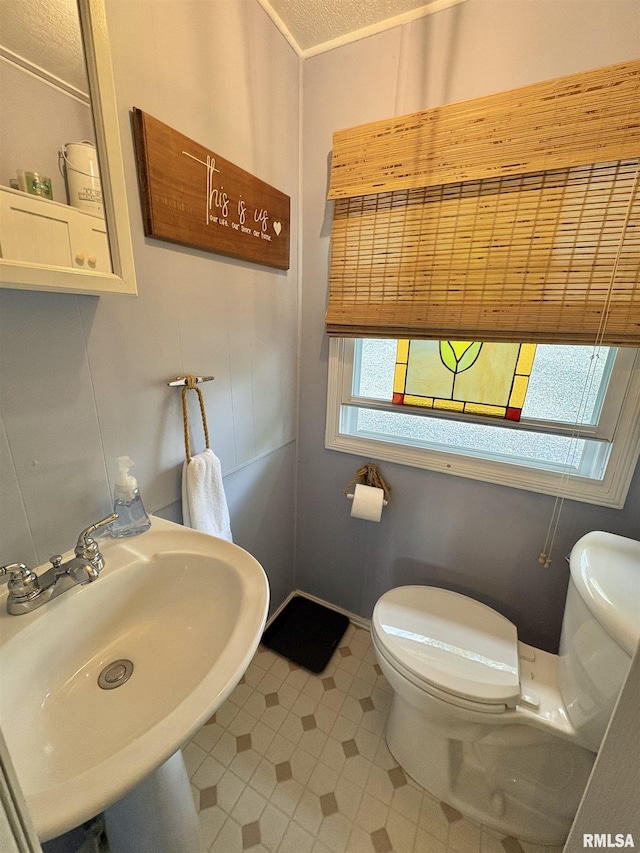 bathroom featuring toilet, tile patterned floors, and a sink