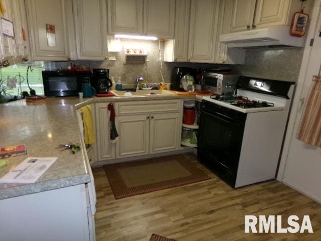 217 Trammel Rd, Carrier Mills, IL 62917 - kitchen featuring black microwave, a sink, light countertops, under cabinet range hood, and gas range oven