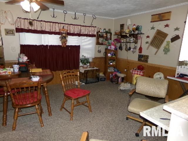 217 Trammel Rd, Carrier Mills, IL 62917 - carpeted dining area featuring crown molding, wainscoting, wooden walls, a textured ceiling, and a ceiling fan