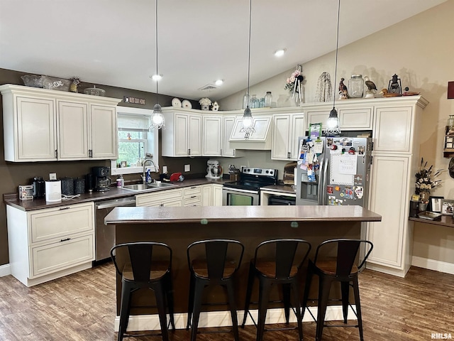 1821 Zion Hill Rd, Centralia, IL 62801 - kitchen featuring appliances with stainless steel finishes, lofted ceiling, a breakfast bar area, a kitchen island, and wood finished floors