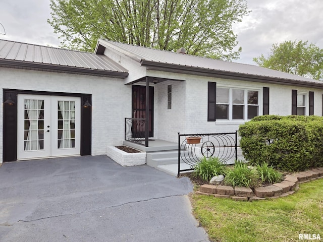 ranch-style home featuring french doors, metal roof, and brick siding