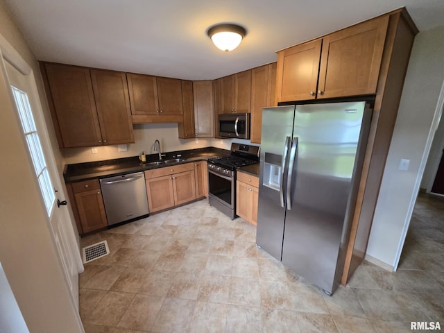 kitchen featuring a sink, dark countertops, stainless steel appliances, and visible vents