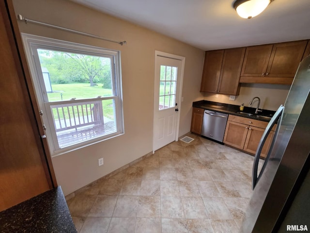 kitchen featuring brown cabinetry, visible vents, a sink, baseboards, and stainless steel appliances