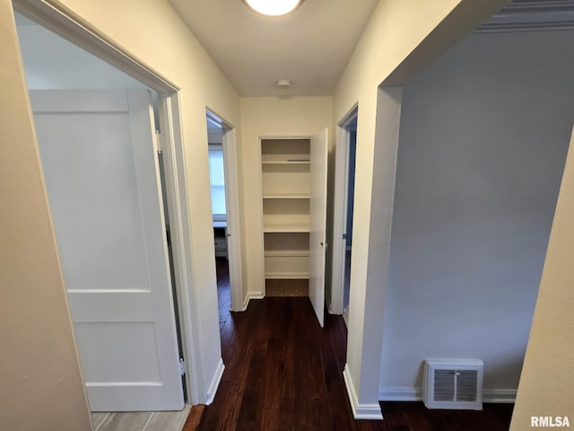 hallway featuring visible vents, baseboards, wood finished floors, and built in shelves