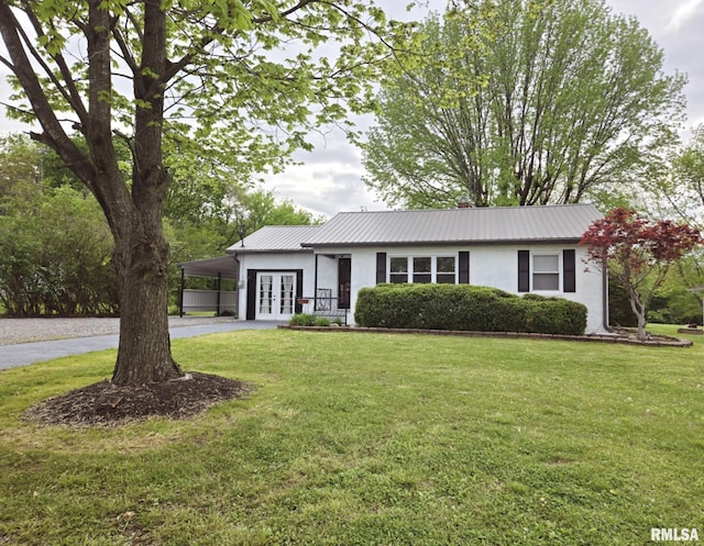 ranch-style house with curved driveway, french doors, a front yard, and metal roof