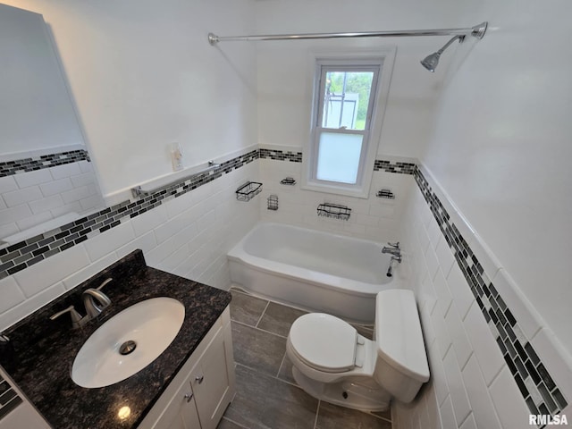 bathroom featuring a bath, tile walls, wainscoting, vanity, and toilet