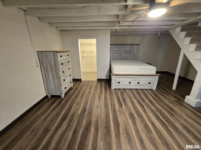 unfurnished bedroom featuring concrete block wall, a ceiling fan, and wood finished floors