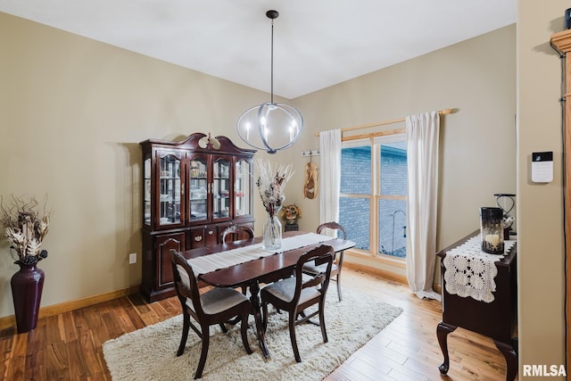 dining room featuring baseboards, light wood-style flooring, and a chandelier