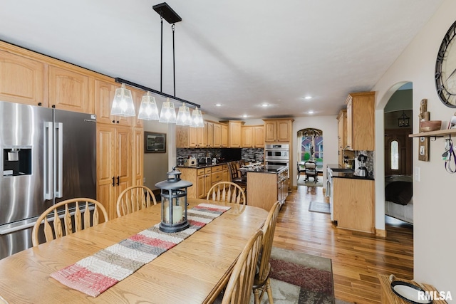 dining room featuring arched walkways, recessed lighting, and light wood-type flooring